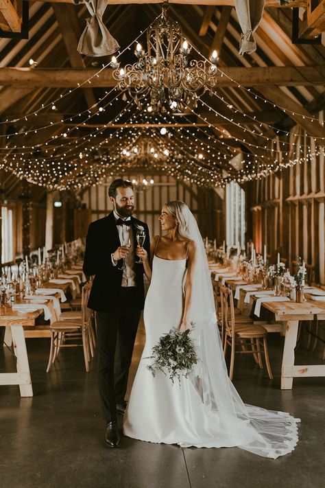 The bride in a fitted wedding gown with thin straps, gold hoops and a veil smiles at the groom as they share champagne in their fairy lit wedding venue Black Tie Wedding Theme, Dark Green Bridesmaid Dresses, Event Nails, Dark Green Bridesmaid, Dresses Event, Dark Green Bridesmaid Dress, Fairy Lights Wedding, Dress Event, Minimalist Wedding Decor