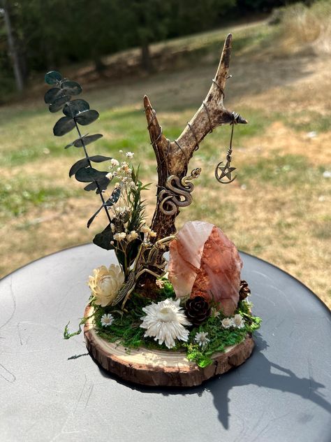 This beauty is mounted in a 5.5" wood slice. It contains a unique Roe Deer antler shed wrapped with a bronze colored craft wire and adorned with a pendant. The piece features a gorgeous fire quartz Freeform crystal, a brass praying mantis and snake, as well as dried flowers.  The praying mantis is often associated with good fortune and luck. In some cultures, the mantis is viewed as symbol of someone who has clairvoyant abilities and is a master of the art of meditation. Fire quartz enhances the ability to find balance, focus, and calm making this duo a perfect pair.  Due to the nature of the crystal and antler used, this piece is truly one-of-a-kind and cannot be replicated. If it calls to you, I highly encourage you to welcome it into your home. Witchy Crafts Diy Projects, Witchy Crafts To Sell, Spooky Drinks, Naturalist Decor, Magical Crafts, Deer Antler Crafts, Oddities Collection, Twig Crafts, Witch Crafts