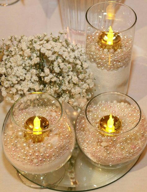 Table decor. We bought all different wine glasses and small vases from thrift stores then filled them with epsom salt and pearls purchased online (very inexpensive). Flameless gold votive candles purchased online. Grandgirl got a great deal on Black Friday. Wedding Pearls Decor, Gold And White Centerpieces, Pearl Party Decorations, Pearl Candle Centerpiece, Half Birthday Candle, Pearl Centerpieces, Ashley Table, Pearl Wedding Decorations, Masquerade Dance