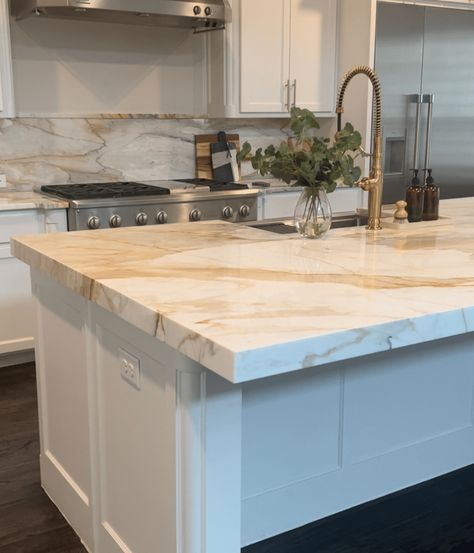 Learn about all the different types of white kitchen countertops. Get inspired by kitchen design ideas for different styles of white kitchens Backsplash With White Marble Countertops, White With Gold Quartz Countertop, White With Gold Countertops, White Gold Granite Countertops, White Kitchen With Quartzite Countertops, White Cabinets Kitchen Countertop Ideas, Calcutta Gold Quartz Countertops And Backsplash, White And Gold Quartzite Countertops, What Countertops Go With White Cabinets