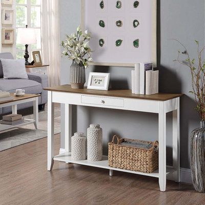 A console table is a versatile accent that works in many places in a home: from an entryway to a cluttered living room and beyond, the console table offers room to display decor pieces while also clearing up clutter. Take this one for example: Crafted from a blend of solid and manufactured wood, it strikes a clean-lined silhouette and boasts a neutral dark brown wood finish. An open bottom shelf provides a place to stack books and more, while a drawer up top keeps tabs on smaller treasured trink Entrance Table Decor Modern, White Console Table Decor, Cluttered Living Room, White Entry Table, White Entryway Table, Entrance Table Decor, Stack Books, Entry Table Decor, White Console Table