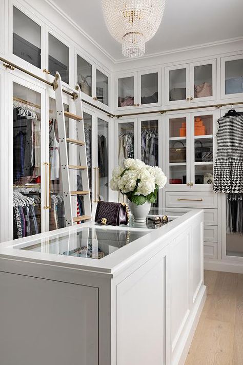 A white closet island with a glass top is lit by a gorgeous clear beaded chandelier. Walk-in Closet Island Ideas, Closet With Island, Master Closet With Island, Closet Island Ideas, Walk In Closet With Island, Transitional Closet, Glass Wardrobe, Closet Island, Custom Dresser