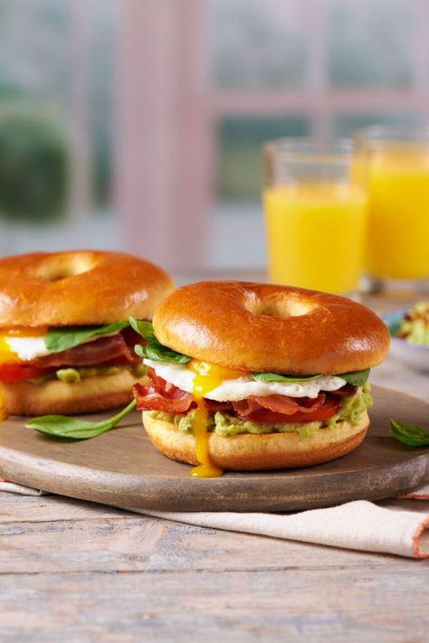 Two brioche bagels on a wooden baord filled with breakfast ingredients in front of a couple of glasses of orange juice. Bagels Breakfast Ideas, Avacodo Breakfast, Brioche Bagels, Bagel Fillings Ideas, Bagel Fillings, Breakfast Brioche, Breakfast Platters, Bob Bon, Bacon Bagel