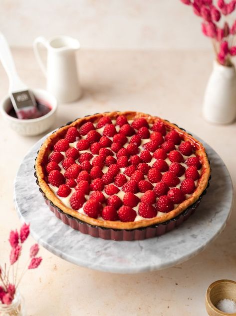 custard tart with fresh raspberries on top of a marble cake stand. Raspberry Custard Tart, Eggless Custard, Raspberry Custard, Raspberry Topping, Gluten Free Shortbread, Raspberry Tart, Plant Based Yogurt, Raspberry Coulis, Vegan White Chocolate