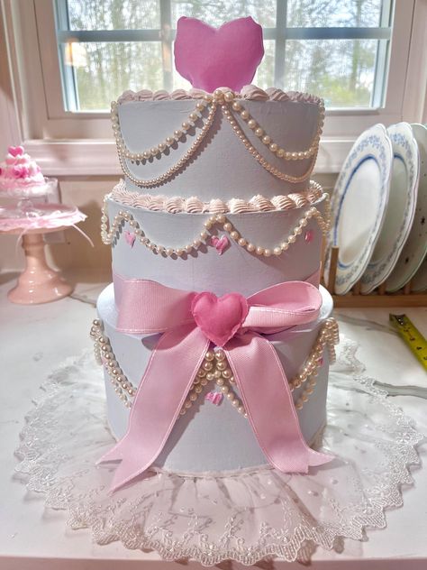 This delicate baby blue 3-tier fake cake stands as an confectionery display 💕Delicate white pearls are meticulously placed along the edges of each tier, adding a touch a sophistication. Both hearts are sewn and stuffed. A large luxurious bow drapes gracefully across the center layer. To compliment this look, a thin lace ribbon flows at the bottom. 🎂❤️Perfect for decoration or eventful accent! H: 14.5 in W: 8 in  Made by Evelyn's Secret Garden This product is copyrighted  This content is origin