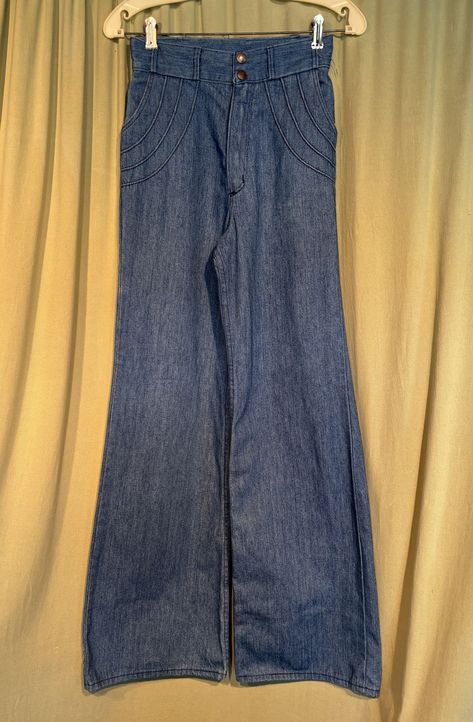 This is a pair of vintage jeans from the 70s. Labeled, Wrangler they are a labeled a size 9/10. Waist 26" Inseam 32", please see measurements below.  Made of blue cotton denim in a medium wash. The pants are high waisted with a double metal snap on the waistband. Metal zipper. The front hip pockets are trimmed with a raised welt design & the patch pockets on the seat have the same welt design. The legs are wide and bell bottoms.   The pants are in good condition. They show minimal wear and no soil. Edges of the legs are not frayed or worn. Measurements were taken with the garment lying flat. if you have never worn vintage before, please measure yourself or a pair of jeans that fit you well. Vintage sizes run smaller than today's sizes.  If you have any questions about measuring, please con 60s Clothing, 70s Pants, 70s Jeans, Seventies Fashion, Jeans High Waist, Jean Vintage, Bottom Jeans, Fire Fits, Older Fashion