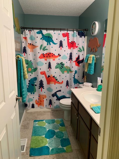 Wall dinosaurs are from Hobby Lobby. The wall clock, shower curtain, bath rug, and towels are from Amazon. The toothbrush holder is from Target. Dino Themed Bathroom, Dinosaur Theme Bathroom, Dino Bathroom Decor, Kid Boy Bathroom, Dino Themed Room, Toddler Bathroom Organization, Dino Bathroom Ideas, Dinosaur Themed Bathroom, Toddler Bathroom Ideas Boys