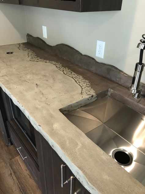 Mountainous backsplashes are a breeze with concrete! These countertops also have a live edge. With endless options for color and design you should choose concrete! #ConcreteCountertops, #CustomDesigns, #KitchenRemodel, #BespokeCountertops, #ModernConcrete, #UniqueSurfaces, #InnovativeDesign, #HomeRenovation, #InteriorDesign, Stylish Countertops, Creative Concrete, Handcrafted Surfaces, Contemporary Decor, bar tops, concrete bar Dark Concrete Countertops, Colored Concrete Countertops, Feather Finish Concrete Countertops, Concrete Bar Top, Stained Concrete Countertops, Unique Countertops, Concrete Bar, Bar Tops, Concrete Countertops Kitchen