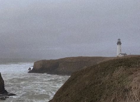 a lone lighthouse sits to the right of the image perched upon rocky cliffs which are covered in brown wintry grass. the sky is gray and foggy, and the ocean crashes against the rocks beneath the lighthouse. the waves are gray and misty. the image gives an aura of both hope and desperation. Foggy Coast Aesthetic, To The Lighthouse Aesthetic, Living By The Sea Aesthetic, Pacific Northwest Gothic Aesthetic, Pacific Northwest Coast, Stormy Sea Aesthetic, Pacific Northwest Gothic, Stormy Island, Tired Tired Sea