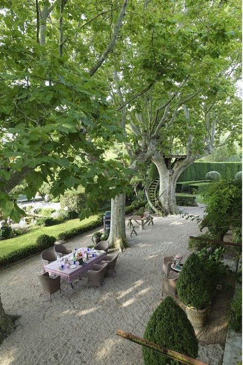 Large trees give an abundance of shade for a dining experience. A dining table is set up for a nice meal. The seating can accommodate six people, and the area is surrounded with other types of plants and bushes.#backyard #backyardideas #backyardlandscaping #backyardgarden Mediterranean Landscape Design, Provence Garden, Gravel Landscaping, Diy Playground, Mediterranean Landscaping, Gravel Garden, French Garden, Outdoor Dining Area, Garden Spaces