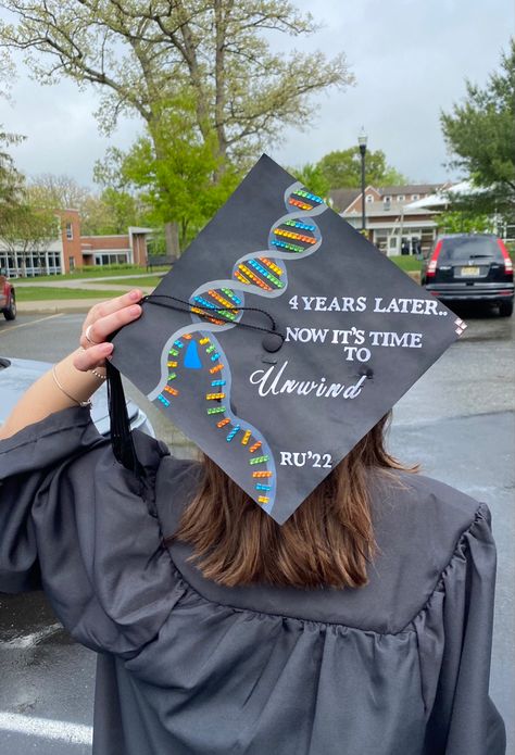 Graduation cap with a DNA helix unwinding by a DNA helicase. To the right of the DNA strand says “4 years later.. Now it’s time to unwind” Bachelors In Biology Cap, Cap Decoration Graduation Biology, Science Graduation Cap Designs, Graduation Cap Designs College Biology, Grad Cap Ideas Biology, Bachelor Of Science Graduation Cap, Graduation Cap Designs Exercise Science, Biology Graduation Party Ideas, Chemistry Graduation Cap Ideas