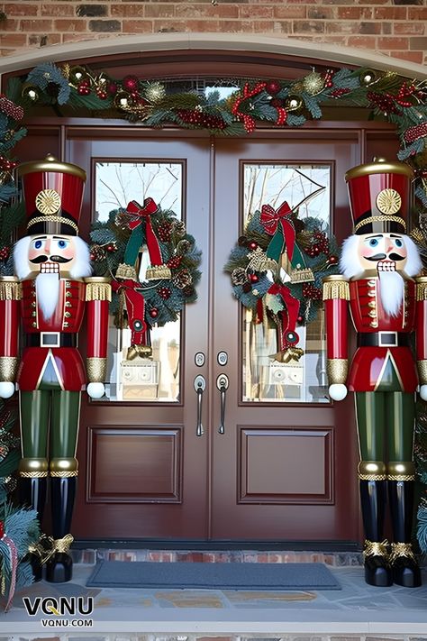 Festive front door decor featuring two majestic nutcracker statues, wreaths with red bows, and lush garlands adorned with ornaments. Front Porch Christmas Decor Nutcracker, Front Door Nutcracker, Christmas Nut Cracker, Nutcracker Christmas Door Decorations, Nutcracker Outdoor Decor Christmas Yard, Nutcracker Themed Christmas Decor Ideas, Christmas Nutcracker Decor, Nutcracker Front Porch, Nutcracker Outdoor Decor