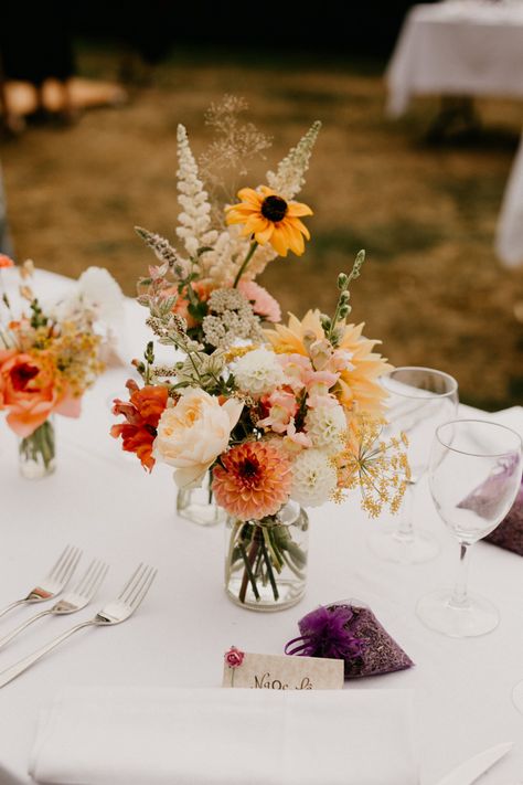 Orange Boho Wedding Flowers, Too Table Wedding Flowers, Orange Spring Wedding Flowers, Orange Yellow White Centerpiece, Colorful Wedding Centerpieces Floral Arrangements, Fall Wildflower Wedding Table, Orange And Yellow Centerpieces, Wedding Decorations Flowers Table, Simple Wedding Centerpieces Spring