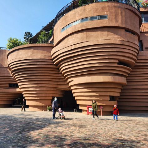 An architectural studio designed the four-story Bat Trang Pottery Museum as a way to pay homage to the traditions of the village that go back to the 11th century. The shape of the building is inspired by the shape of pots created on a potter's wheel and the terracotta colour references the earthen material and bricks used to build kilns. I spent a lovely day exploring this village which began first with a stop at this museum, which luckily also had some ongoing exhibitions, where local artisa... Pottery Architecture, Pottery Exhibition, Pottery Museum, Terracotta Colour, Architectural Studio, Architecture Collage, Brick Facade, 11th Century, Pottery Wheel