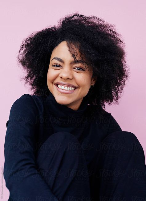 Portrait of a confident happy young woman with Afro on pink in studio. She is smiling and looking at the camera. She is sitting with her arms around her legs. Color Photography Portraits, Happy Headshots, Comedy Headshots, Happy Portrait Photography, Simple Portrait Photography, Smiling Portrait Photography, Colorful Headshots, Fun Headshots, Woman With Afro