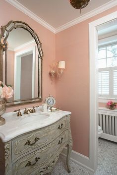 Pretty soft coral bathroom by RLH Studio. Ralph Lauren Acacia Grass-Ballet Slipper wallpaper. Ceiling & trim: BM's Cloud White. French dresser fitted with a sink. Uttermost Petrizzi mirror (antiqued silver leaf w/ gray glaze). Venetian/Murano glass sconces bought in Italy. [Some coral paint choices: Behr Victorian Blush, SW Mellow Coral 6324, BM Rosestone]. Commode Shabby Chic, Traditional Powder Room, Country Bathroom Designs, Powder Room Design Ideas, French Bathroom, Pink Bathroom Decor, French Country Bathroom, Coral Walls, Powder Room Design