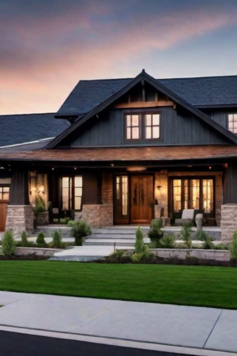 Modern two-story house with dark wood exterior, large front porch, stone accents, and a well-manicured lawn at sunset. Cedar And Rock Exterior, Home Exterior With Black Windows, House With Stone Accent Exterior, Moody Farmhouse Exterior, Black And Brown House Exterior, Mountain Farmhouse Exterior, Light Exterior House Colors, Modern Rustic Exterior House, Black Craftsman House