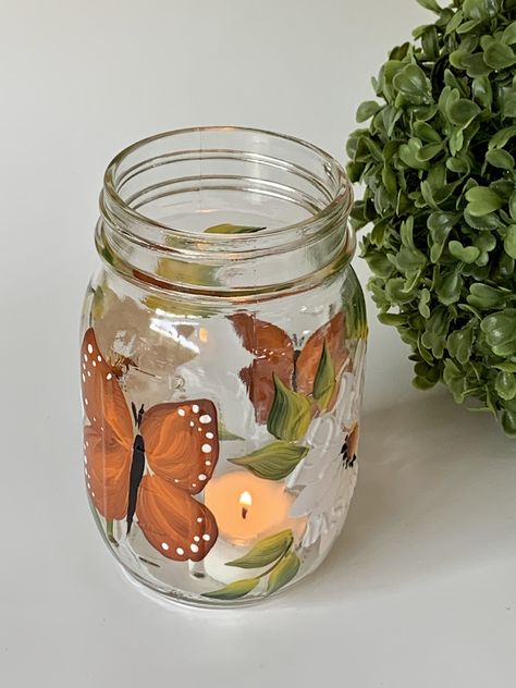 Glass mason jar with handpainted white daisies and butterflies, very happy design. Listing is for one jar with light. They are great as a decorative piece. Remove lights and use for candy or cookies. Wonderful for the bathroom as a toothbrush holder, great for spring and summer, very neutral. Great to use for mixed drinks, wine , sangria etc. Makes a great lemonade jar. Multiple usages, pretty and useful! They are great for gift giving, Jar Painting Ideas Cute Aesthetic, Cute Jar Painting Ideas, Cute Mason Jar Painting Ideas, Light Up Mason Jars, Jar Painting Ideas Cute, Mason Jar Painting Ideas, Glass Jar Painting, Painting Mason Jars, Mason Jar Painting