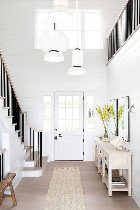 A white front door accented with 9 glass panels is flanked by sidelights and opens to a foyer boasting white shiplap walls and staggered white lights hug over a fringe jute runner. Pretty Beach House, Style Me Pretty Living, Timeless Interiors, Custom Furniture Design, Foyer Decorating, Entrance Foyer, Entry Way Design, Waterfront Homes, Island Home