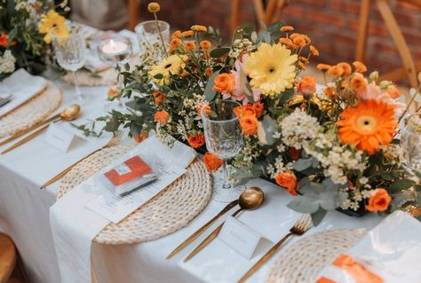 A retro 70's-esque wedding guest tablescape décor with autumnal tones. A rattan placemat, gold cutlery, tealight candles and a personalised menu. Beautified with a floral table centerpiece of gerberas, daisies, and eucalyptus leaves. Daisy Wedding Centerpieces, Gerbera Wedding, Gerbera Daisy Wedding, Rattan Placemat, Gold Cutlery, Tealight Candles, Floral Table, Spring Theme, Gerbera Daisy