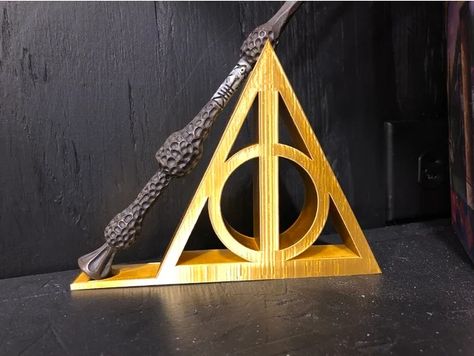 A Deathly Hallows inspired wand holder. Should hold most Harry Potter style wands.5/15 EditAdded two extra stl files.DH wand stand extra support.stl has a lip at the end of the stand to help support a wand betterDH wand stand thick base.stl has a thicker base to aid in supporting a wand better. Wand Stand, Harry Potter Diy Decorations, Wall Decor Game Room, Harry Potter 3d, Wand Holder, Deathly Hallows Symbol, Elder Wand, Art Harry Potter, Diy Harry Potter