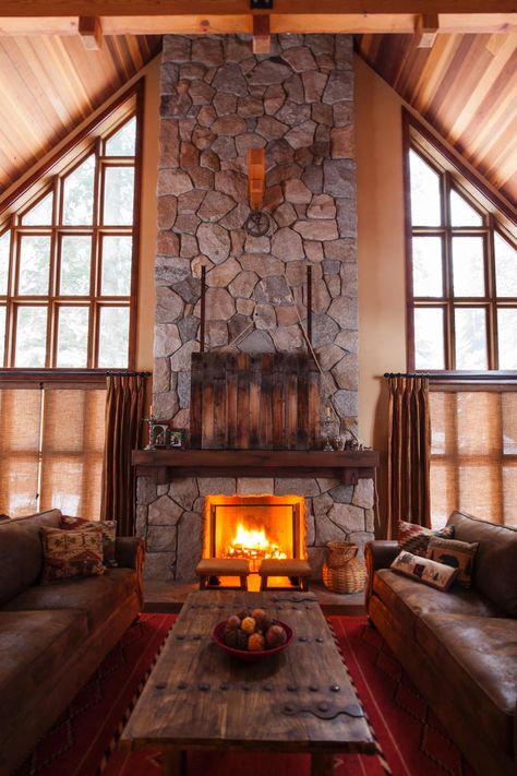 Hidden TV--A towering stone fireplace draws you into this lodge-style living room. Leather sofas are topped with Southwestern pillows, while a clever pulley system above the mantel conceals the TV behind a reclaimed wood screen. Craftsman Style Homes Interior Decor, Corner Stone Fireplace, Corner Fireplaces, Corner Fireplace Ideas, Rustic Stone Fireplace, Stone Fireplace Designs, Fireplace Design Ideas, Cabin Fireplace, Masonry Fireplace