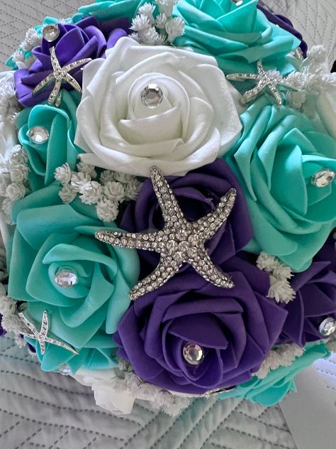 "This bouquet measures 11\" in diameter and 11\" tall. The colors are purple, turquoise and white. Each rose has a rhinestone its center.  There is a large 2\" Rhinestone Starfish brooch in the center as well as pave rhinestone starfish pins scattered around the bouquet.  The blinged handle has a white satin ribbon.   A wonderful addition to your themed event. The real touch roses are terrific if you are having a destination wedding as well. Their shape holds up even if they become squashed in t Mermaid Theme Wedding, Purple Orchid Bouquet, Sea Wedding Theme, Blue And Purple Orchids, Purple Turquoise Wedding, Beach Wedding Purple, Little Mermaid Wedding, Bling Bouquet, Quinceanera Bouquet