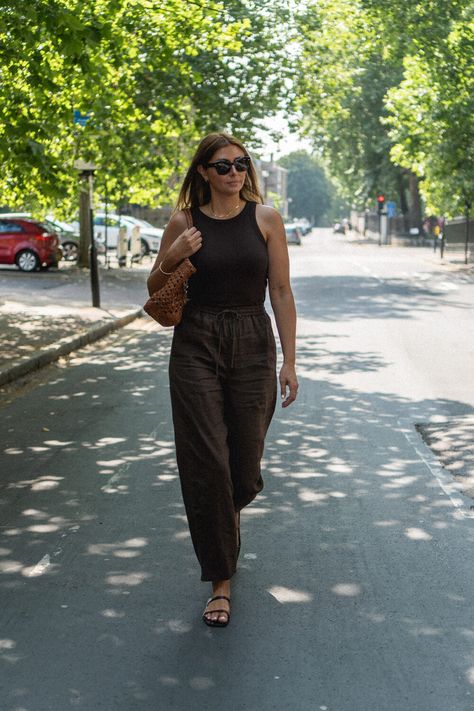 Emma Hill wears brown linen trousers, brown racer back vest top, strappy sandals, Dragon Diffusion Cannage tote bag in tan woven leather. Casual Summer outfit Brown Linen Pants Outfit, Strappy Sandals Outfit, Brown Trousers Outfit, Brown Linen Pants, Brown Pants Outfit, Emma Hill, Neon Leggings, Black Linen Trousers, Linen Pants Outfit