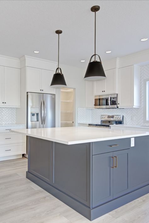 This beautiful kitchen features white quartz countertops, white cabinets with grey island, stunning black feature pendants, herringbone tile backsplash and gold faucet White Kitchen Cabinets Black Countertops Grey Floor, White Kitchen And Grey Island, White Cabinet Grey Island, White Dark Grey Kitchen, Kitchen White Cabinets Grey Floor, Kitchen Grey And White Cabinets, Decorative Backsplash Kitchen, Black White Grey Gold Kitchen, Light Grey Tiles Kitchen