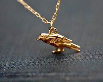 A richly detailed gold raven charm necklace. Crow Pendant Necklace, Ajr Concert, Universal Symbols, Crow Jewelry, Crow Pendant, Crow Necklace, Raven Jewelry, Raven Pendant, Raven Necklace