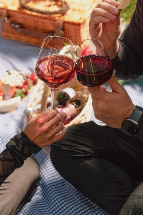 A couple sitting on a picnic blanket with a spread of food and glasses of non-alcoholic wine in front of them. They are holding up glasses and appear to be enjoying a wine tasting experience. Wine And Cheese Pairings, Wine Date, Fun Date Ideas, Romantic Wine, Colored Wine Glasses, Wine Picnic, Romantic Picnic, Wine Christmas, Non Alcoholic Wine