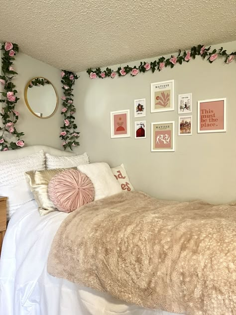 Dorm room with pale green walls, bed with pink and white bedding and throw pillows, faux pink roses and leaves hanging down walls, over bed, gallery wall by bed of pink and white art Nyc Dorm Room, Floral Dorm Room, Hot Pink Dorm, Double Dorm Room, Unc Dorm, Nyc Dorm, Pink Dorm Room Ideas, White Dorm Room, Pink Dorm Room