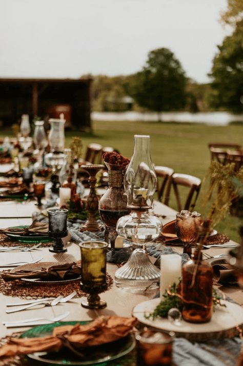 This moody cottage core wedding had the perfect al fresco tablescape! We love the vintage glassware and foraged florals. Check out more outdoor dining ideas on our blog. Boho Thrifted Wedding, Bohemian Table Setting Wedding, Cottage Core Forest Wedding, October Moody Wedding, Fall Wedding Farmhouse, Earthy Wedding Inspiration, Antique Rustic Wedding, Thrifted Wedding Bridesmaid Dresses, Summer Cottage Wedding