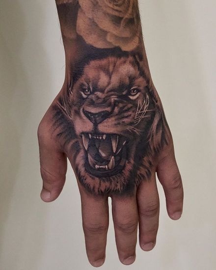 Discover the world of lion tattoos in our article. From deep symbolism and rich history to placement options and best designs. Lion Hand Tattoos For Guys, Lion Head Hand Tattoo, Big Hand Tattoos Men, Hand Tattoos Lion Men, Lion Hand Tattoo Design, Hand Lion Tattoo Design, Lion Tattoo Man, Back Hand Tattoo Men, Lion Hand Tattoo For Women