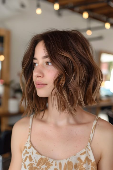 Woman with shoulder-length wavy hair in a brightly lit room with hanging lights. Bob With Light Brown Highlights, Highlights On Short Dark Brown Hair, Highlights For Brown Hair Curly, Mini Highlights Hair Brown, Short Dark Hair With Blonde Highlights, Lowlights For Brunettes Short Hair, Short Hair Balayage Brunette Caramel, Caramel Balayage Black Hair, Ombre Bob Brunette