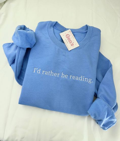 Elevate your bookish style with our "I'd Rather Be Reading" embroidered sweatshirt, a minimalist delight for book lovers. This thoughtful book club gift seamlessly blends comfort and literary charm, making it the perfect addition to your wardrobe for cozy reading sessions and guaranteed satisfaction. Color in example is Carolina Blue * 50% cotton, 50% polyester * Pre-shrunk * Classic fit * 1x1 athletic rib knit collar with spandex * Air-jet spun yarn with a soft feel and reduced pilling * Double Book Crewneck, Book Sweatshirts, Book Club Sweatshirt, Bookish Clothing, Book Nerd Sweatshirt, Book Lover Sweatshirt, Bookish Crewneck, Gift Ideas For Book Lovers, Reading Sweatshirt