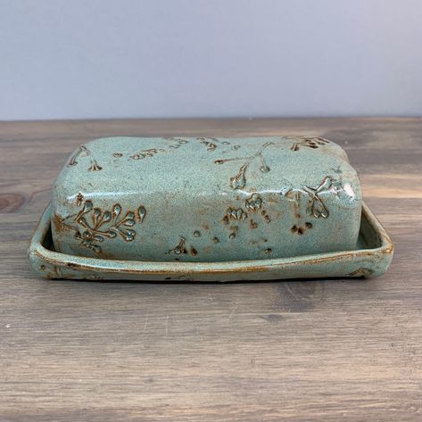 "Elevate the tabletop with this handmade modern pottery butter dish. It's a functional dish to serve up the butter while bringing an earthy, natural vibe to the table.  It keeps a standard stick (1/2 cup) of butter covered and stored in the refrigerator.  The stoneware dish is imprinted with fresh plant cuttings and glazed with a satin surface. The bottom shows off the natural red clay from which it is formed. What a perfect artisan kitchenware gift for the mom who loves to cook!  6.5\" x 3.5\" x 2\" Durable stoneware pottery Dishwasher safe & microwave safe Carefully, beautifully and responsibly packaged From my studio to your home, each butterdish is unique and thoughtfully made from slabs of clay that have been rolled and shaped by hand.  Patterns are made by pressing natural fresh clip Hand Built Pottery Gifts, Handmade Ceramic Kitchenware, Hand Built Pottery Butter Dish, Handmade Ceramic Butter Dish, Ceramic Cookware Handmade, Hand Built Bowls Pottery, Air Dry Clay Butter Dish, Handmade Butter Dish, Ceramic Butter Dish Handmade