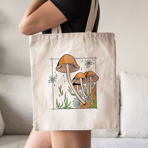 This Mushrooms Tote Bag is a stylish upgrade to reusable tote bags.  This Cottagecore Inspired mushroom canvas tote bag make a great reusable tote for yourself or as a gift tote.  ⚡ USA fast delivery. We deliver within a week. ⚡ Our Tote Bags are made with 100% cotton sheeting. Add their reinforced handle stitching to the mix, and you got a reliable bag rich in both practicality and durability. These durable totes are crafted with a last technological DTG printer for a vibrant flawless finish. T Mushroom Tote Bag, Tote Bag Ideas Design, Beach Tote Bags Diy, Tote Bag Design Ideas, Handpainted Tote, Diy Tote Bag Design, Bachelorette Tote Bags, Painted Canvas Bags, Bachelorette Tote