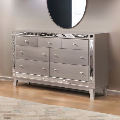 With this elegant dresser, your bedroom will exude glam and sophistication. Constructed from poplar wood, Asian hardwood, and select woods in a chic, mercury-silver metallic finish, the dresser features seven drawers that provide more than enough space for all of your clothing and accessories. Its mirrored panel accent borders the front of a dresser to pair beautifully with the finish and provide more light and a greater sense of depth to your room. With the addition of this dresser, you will cr Glass Dresser Bedroom, Grey Dresser Bedroom, Mirrored Furniture Bedroom, Chest Drawers Bedroom, Silver Bedroom Furniture, White And Silver Bedroom, Silver Living Room, Mirror Dresser, Silver Dresser