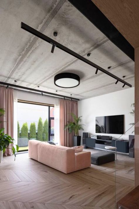 This living room has a unique design that feels modern industrial and feminine with pink furniture. The living room interior features an area rug that gives off a cozy feel, and the large glass walls showcase the surrounding. The sofa and ceiling lamps and concrete ceiling are purposely left unpainted to create a rough texture. #LivingRoomDesigns #LivingRoomIdeas Concrete Ceiling Living Room, Ceiling Interior, Beautiful Living Room Ideas, Concrete Ceiling, Pink Furniture, Concrete Walls, Rough Texture, Glass Walls, Living Room Design Ideas