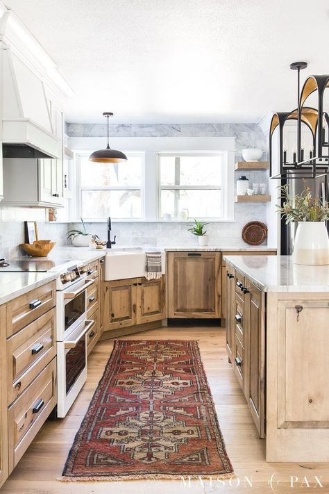 Get all the sources for this beautiful white and wood kitchen with white oak flooring, black and gold accents, marble backsplash, and quartzite counters. Wood Kitchen Cabinets White Appliances, Maple Cappuccino Cabinets, Adler Wood Cabinets, White And Wood Kitchen Cabinets, Kitchen With Natural Wood Cabinets, Natural Maple Kitchen Cabinets, White And Wood Cabinets, White And Oak Kitchen, Natural Kitchen Cabinets