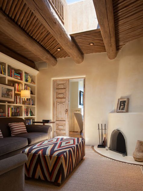 This cozy sitting room off the master suite features classic Southwestern touches, such as a kiva fireplace, hand-plastered walls, and carved wooden doors. A stunning skylight brightens up the space during the day. Modern Adobe House Exterior, Adobe House Exterior, Modern Adobe House, Adobe House Plans, Modern Southwest Style, Santa Fe Decor, Modern Adobe, Santa Fe Style Homes, Adobe Interior