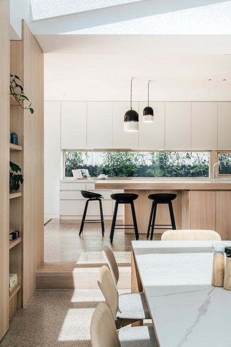 A modern kitchen with minimalist white and wood cabinets, and a window that acts as a backsplash. Window Backsplash, Small Townhouse, Modern Kitchen Window, Townhouse Kitchen, Modern Kitchen Open Plan, Kitchen Window Design, Built In Bathtub, Family Dining Rooms, Design Del Prodotto