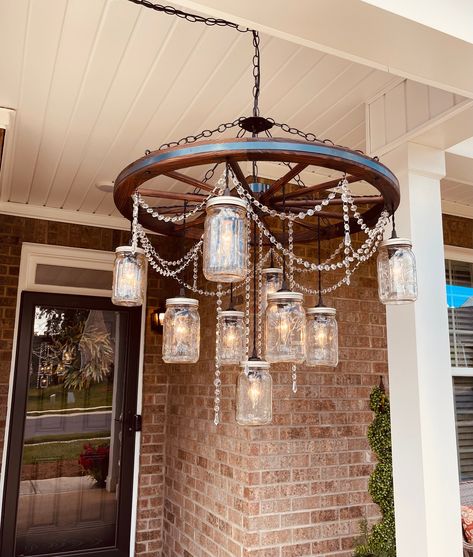 Large wagon wheel chandelier with mason jar lights. The wheel is 32" in diameter and is a natural stain color. There is a metal band accent around the wheel. There are 3 tiers of 9 mason jar lights. It comes with 9 clear quart sized mason jars as shown. The length of the chandelier is about 35" and comes with about 5 feet of cord and chain for hanging. The crystal beading is included and is attached to the wheel using small hooks. The ceiling plate is included as shown.  *Light bulbs are not inc Large Wagon Wheel Chandelier, Mason Jar Lights, Mason Jar Chandelier, Horse Barn Plans, Quart Size Mason Jars, Outdoor Chandelier, Wheel Chandelier, Wagon Wheel Chandelier, Colorado Homes