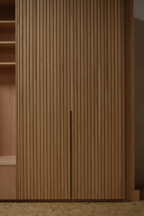 This fitted furniture project in custom veneered oak features intricate solid oak reeded doors. A clever, compact design with library shelves, seat nook and large storage cabinet. Dry-fit and quality checked before whitewashing and spray lacquering. Designed and handcrafted in our studio and workshop in South London. ​ Reeded Door, Reeded Wardrobes, Slatted Wardrobe Doors, Fluted Sliding Wardrobe, Reeded Cabinets, Fluted Panel Wardrobe, Fluted Wardrobe Doors, Wooden Slat Wardrobe Doors, Slated Door Wardrobe