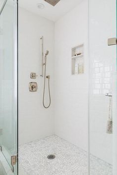 White and gray river rock shower floor tiles invite a stunning pebbled finish contrasted with white subway tiles and a satin nickel shower kit. Shower With River Rock Floor, River Rock Shower Floor, Rock Shower Floor, Shower Floor Tiles, River Rock Shower, Pebble Shower Floor, White Subway Tile Shower, Rock Shower, Restroom Remodel