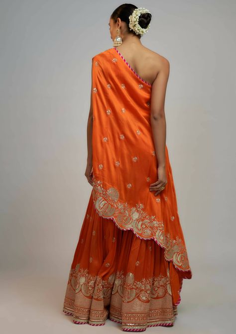 This stylish indo-western set blends bold femininity with a smart, one-shoulder top paired with sharara featuring delicate gold embroidery. Tailored for events, providing the versatility to flow seamlessly with your movements and leave a lasting impression. Orange Sharara, Western Hairstyles, Anarkali Lehenga Gowns, Mehendi Outfit, Anarkali Lehenga, Celebrity Closet, Suits Design, Bride Accessories, Sharara Set