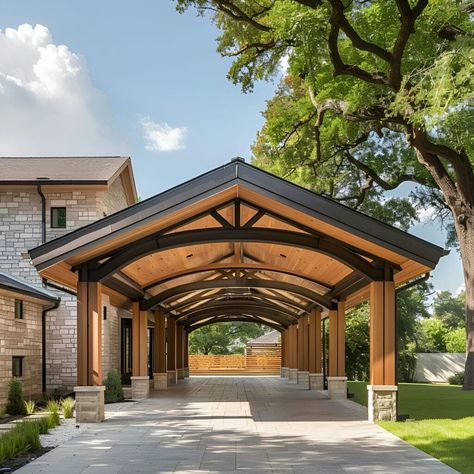 Elegant wooden carport with steel beams and shou sugi ban roof, set against a stone-clad Texas home. Surrounded by lush greenery, it features a gabled design with natural wood accents and dark metal details, enhancing its modern architecture. Shot in bright sunlight, it perfectly blends functionality with aesthetic appeal. Steel Porch Ideas, Covered Driveway Ideas, Car Port Attached To Home, Cool Carport Ideas, Drive Through Carport, Rustic Carport, Modern Gable Facade, Cool Carports, Attached Carport Ideas Garage Addition