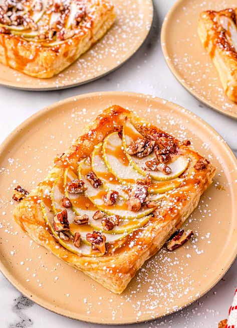 This easy Apple Tart recipe has all the rich fall flavor you’re looking for. A light, flaky, puff pastry crust covered in a honey cinnamon butter, and topped with apples, pecans, and sticky sweet caramel sauce… Are you drooling yet?! This apple dessert is perfect for any apple lover. Delicious any time of day or night, serve this apple tart as breakfast, brunch, or dessert for a dish that will delight! // Mom On Timeout Fall Apple Pastries, Upside Down Apple Tart With Puff Pastry, Apple Tarts With Puff Pastry, Caramel Apple Pastry, Apple Upside Down Puff Pastry, Apple Tart Tatin Puff Pastry, Upside Down Puff Pastry Desserts, Caramel Apple Puff Pastry Recipes, Upside Down Apple Tart