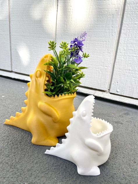 👉👉 Looking for some Jurassic charm to spice up your home decor or office? Look no further than our hungry dinosaur collection! First, meet our new best friend, the Dinosaur Planter! He's so hungry for sunlight, that he'll make sure your plants get all the light they need to grow big and strong. This little guy is just raring to go and ready to hold your favorite plant! With his big mouth, he'll chomp down on any small succulent or flower you give him. Just don't forget to water him or he might Dinosaur Planter, Dinosaur Collection, Cooking Utensil Holder, Cool Dinosaurs, First Meet, Pencil Organizer, Cooking Utensil, Types Of Plastics, Kitchen Cooking Utensils